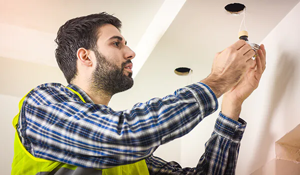 Ein Mann installiert einen LED-Einbaustrahler in die Decke